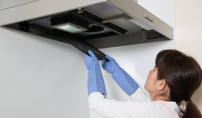 Woman in white shirt and blue gloves opening air duct