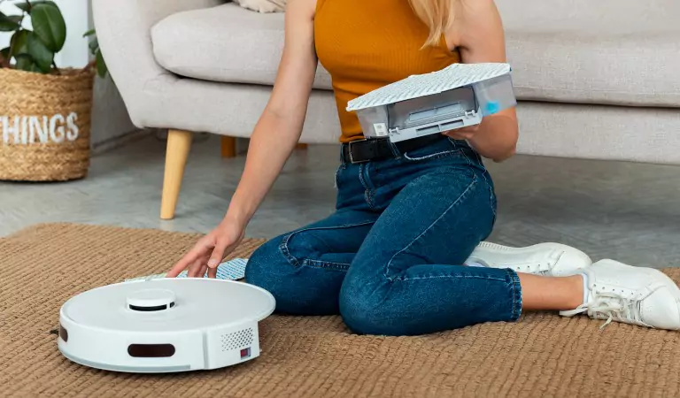 cropped picture of a woman using a robot vacuum cleaner