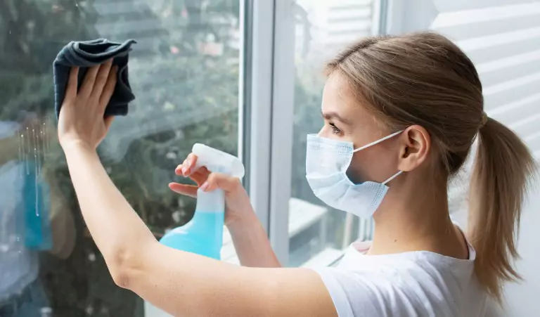 young woman cleaning window glass