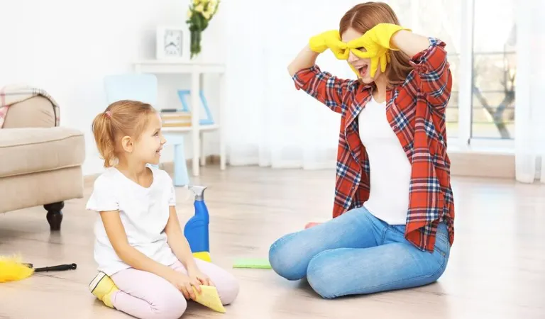 Woman in red shirt, blue jeans and yellow gloves making fun with her kid.