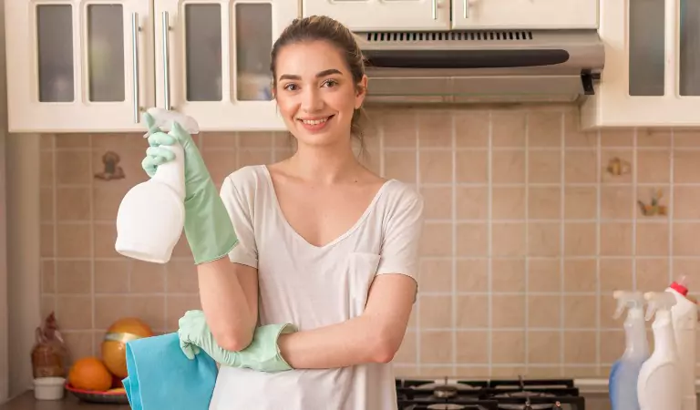 woman with a cleaning spray inside of a kitchen