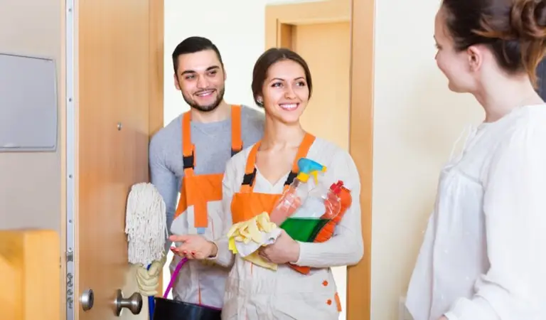 A lady is welcoming professional cleaners into her home.