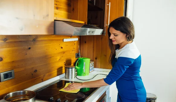 Side view of woman cleaning stove in kitchen at home