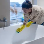 A woman doing cleaning at home and disinfecting the bathroom