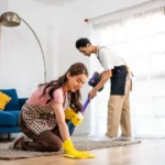 Asian attractive young man and woman cleaning house indoors together happy family vacuuming messy dirty floor for housekeeping housework