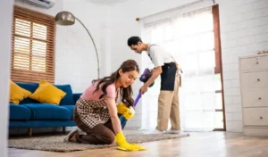 Asian attractive young man and woman cleaning house indoors together happy family vacuuming messy dirty floor for housekeeping housework