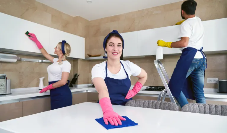 Professional cleaners in blue uniform washing floor and wiping dust from the furniture at apartment. Cleaning service concept